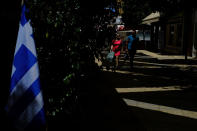 A couple walk on Ledra street a main shopping street as a Greek flag is seen on a Tavern in central Capital Nicosia, Cyprus, Monday, May 25, 2020. Cyprus took a major step toward a return to normality on Thursday when most restrictions of a two month-long stay-at-home order were lifted, allowing primary school kids to return to classes and hair salons and outdoor cafeterias to re-open. (AP Photo/Petros Karadjias)