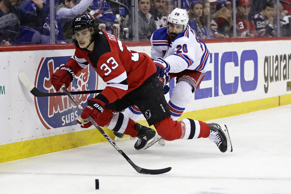 New Jersey Devils defenseman Ryan Graves and New York Rangers left wing Chris Kreider (20) battle for the puck during the first period of Game 7 of an NHL hockey Stanley Cup first-round playoff series Monday, May 1, 2023, in Newark, N.J. (AP Photo/Adam Hunger)