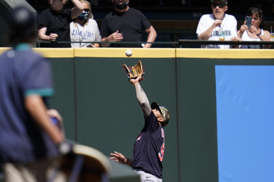 Cleveland Indians left fielder Eddie Rosario snags a fly ball deep into the corner for an out in the first inning of a baseball game Sunday, May 16, 2021, in Seattle. (AP Photo/Elaine Thompson)