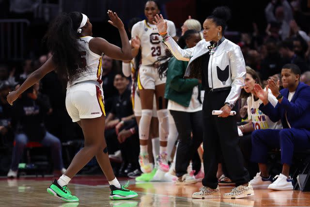 <p>Steph Chambers/Getty</p> Dawn Staley high-fives Raven Johnson