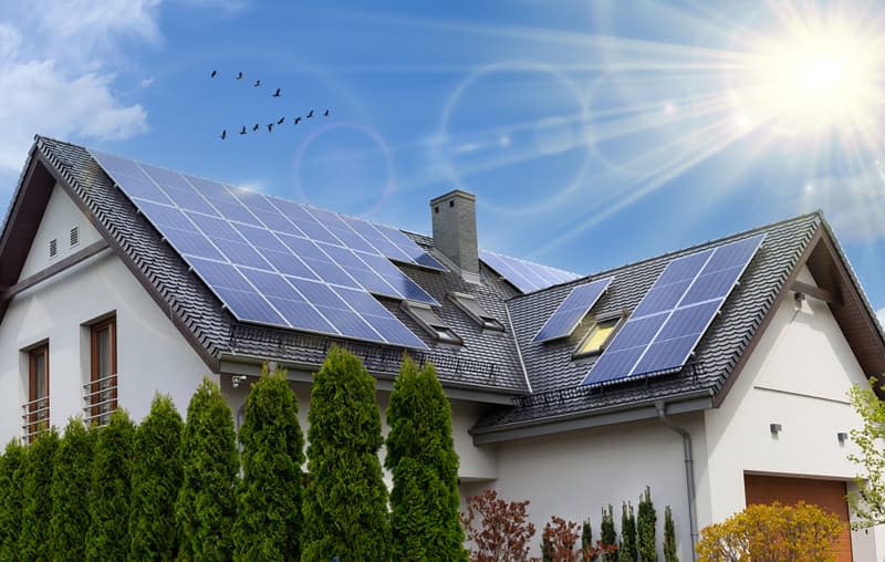 Solar panels on a gable roof. Beautiful, large modern house and solar energy. Rays of the sun.