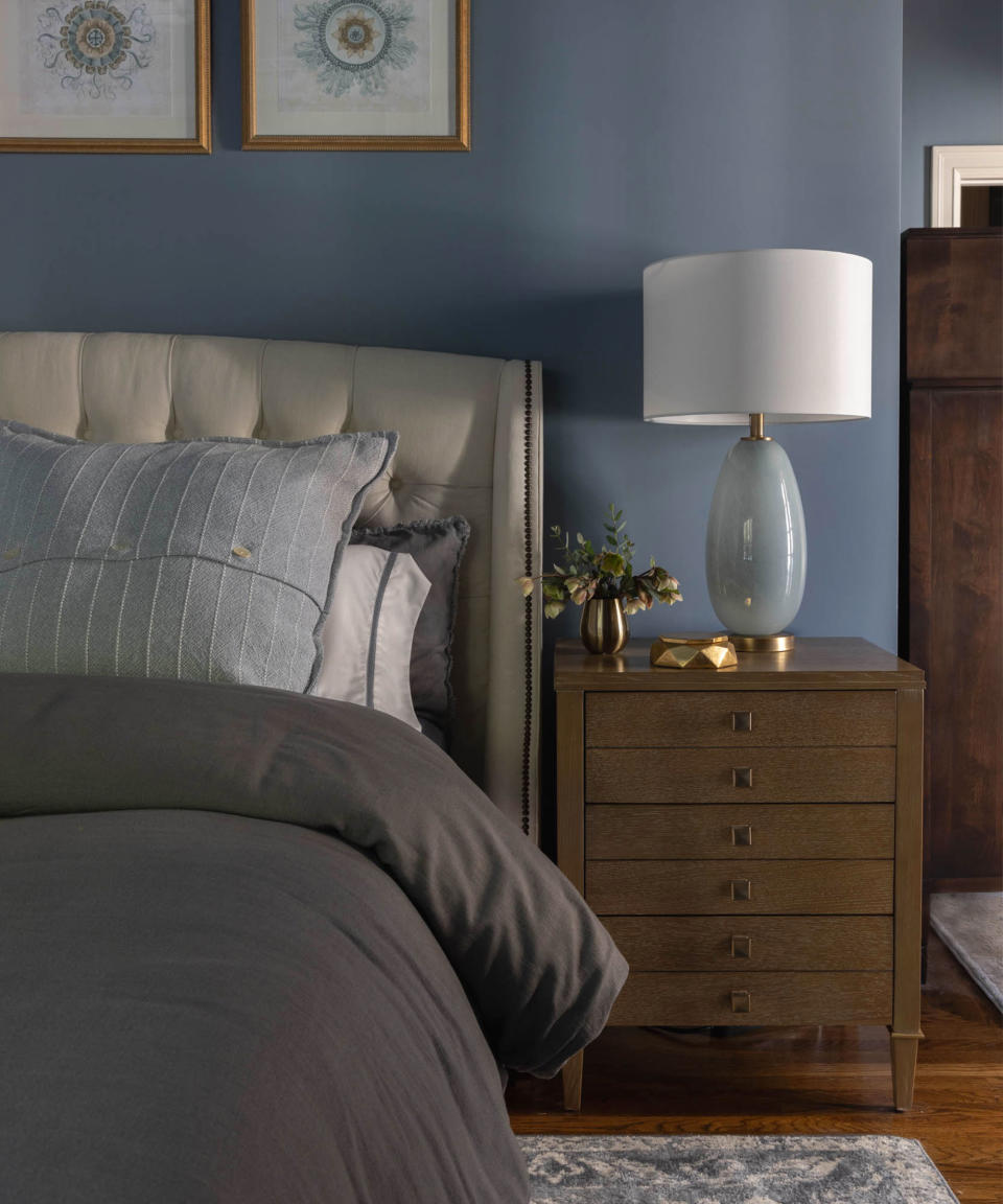Blue bedroom with wooden bedside furniture, artwork on walls