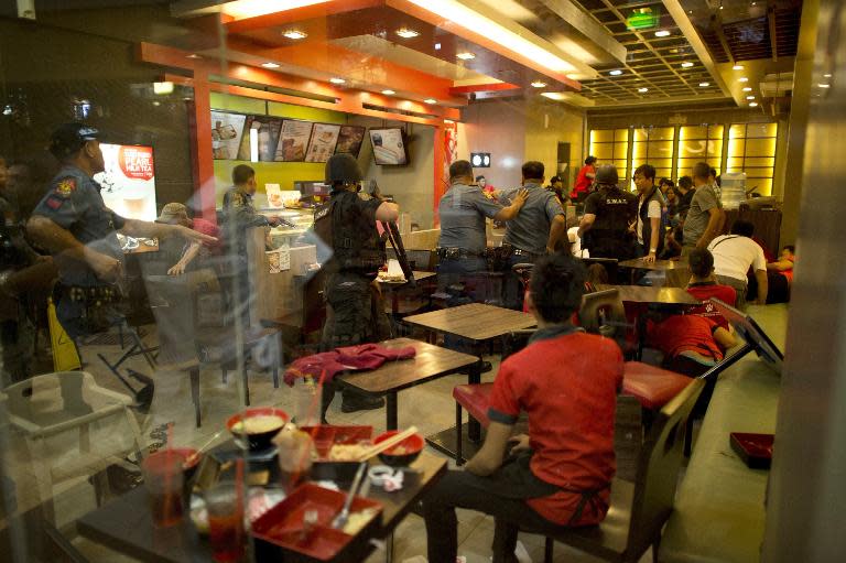Diners rush from a restaurant as members of the Philippines police move towards the scene of an attempted robbery on a jewellery store inside one of the world's largest shopping malls in Manila on March 30, 2014