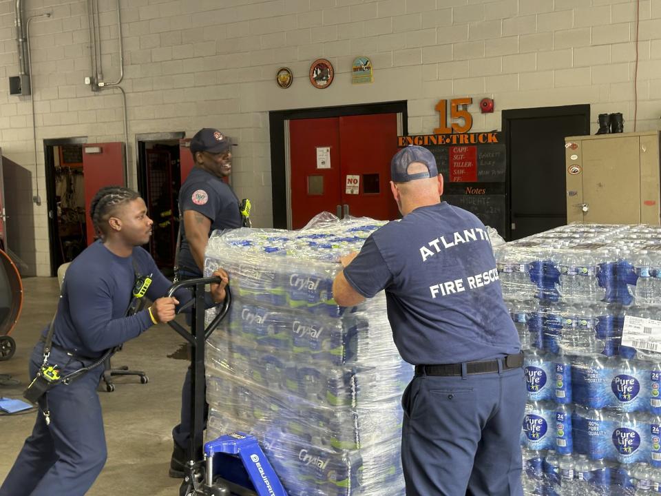 Atlanta firefighters unload bottled water to distribute to residents at a fire station in the city's Midtown neighborhood on Monday, June 3, 2024. The device was one of several used to shut off flow to a leak that had gushed for more than two days in Atlanta's Midtown neighborhood. (AP Photo/Jeff Amy)