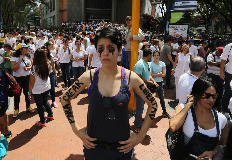 An opposition protester stands in silence with her arms painted with the words in Spanish "To create freedom" during a protest in Caracas, Venezuela, Saturday, Feb. 15, 2014. Demonstrators are protesting the Wednesday killings of two university students who were shot in different incidents after an anti-government protest demanding the release of student protesters arrested in various parts of the country. (AP Photo/Fernando Llano)