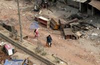 People walk on a road past damaged furniture in a riot affected area following clashes between people demonstrating for and against a new citizenship law in New Delhi