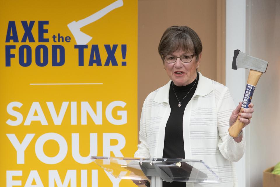 Gov. Laura Kelly holds up an axe, which has played a major role in her campaign for re-election.