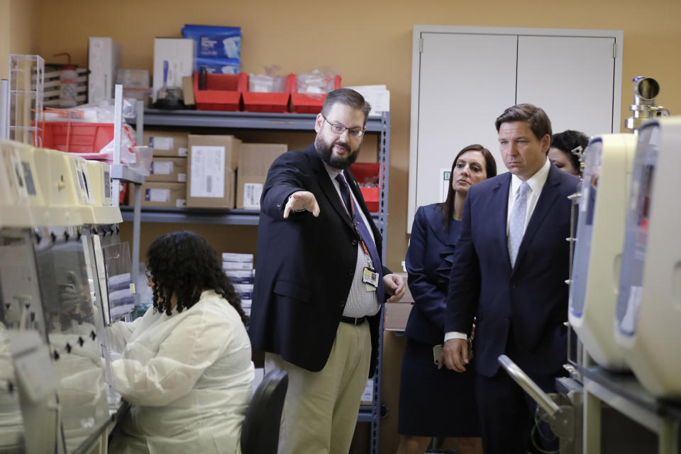 Florida Gov. Ron DeSantis, right, takes a tour of Florida's Bureau of Public Health Laboratories with the Director, Stephen White, where the COVID-19 virus is tested on Monday, March 2, 2020, in Miami. (AP Photo/Brynn Anderson)