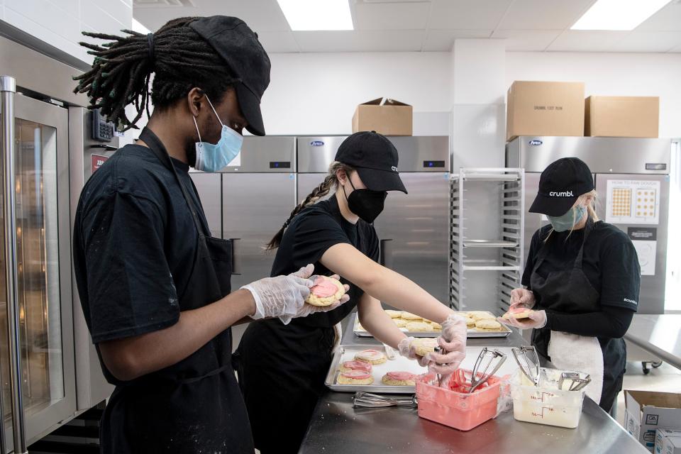 From left, JT Early, Ari Juedeman and Yelena Serdyukov practice frosting cookies at Crumbl in Asheville January 26, 2022.