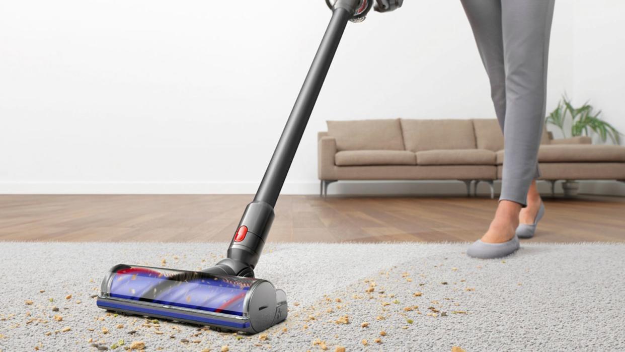  Dyson V8 vs Dyson V10: a Dyson V10 vacuuming cereal and debris off a gray carpet. 