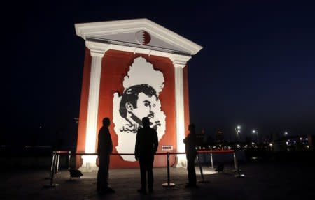 FILE PHOTO: People look at an artwork depicting QatarÕs Emir Sheikh Tamim Bin Hamad Al-Thani during the Winter Festival at Katara Cultural Village in Doha, Qatar, January 18, 2018. REUTERS/Naseem Zeitoon//File Photo