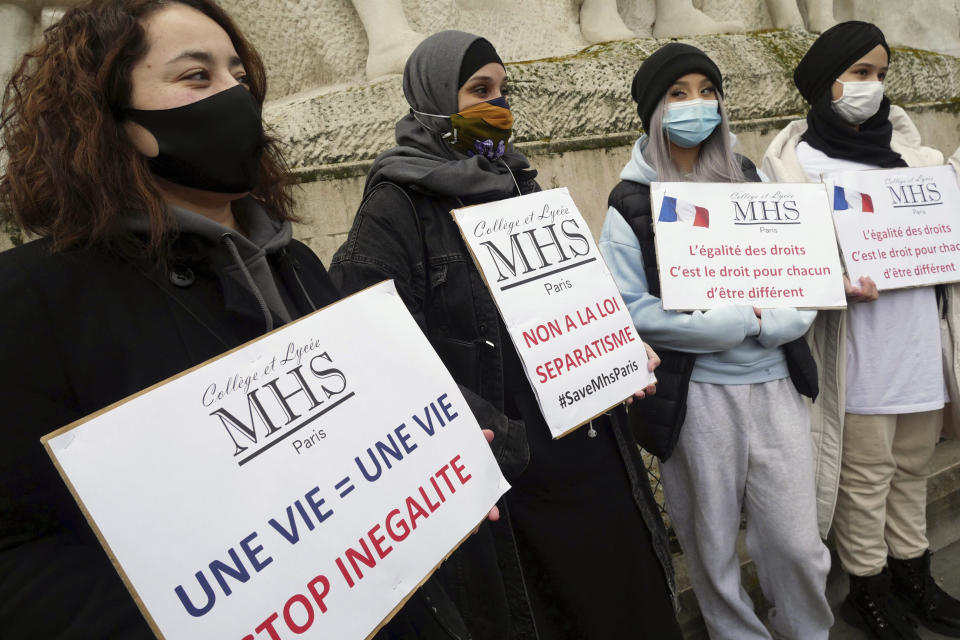 Activists hold placards reading « No to the separatism law » in the center, and « Equality of rights is the right of everyone to be different » on the right, during a gathering in Paris, Sunday, Feb. 14, 2021. Activists rallied Sunday in Paris to demand that the French government abandon a bill aimed at rooting out Islamist extremism that the protesters say could trample on religious freedom and make all Muslims into potential suspects. (AP Photo/Thibault Camus)