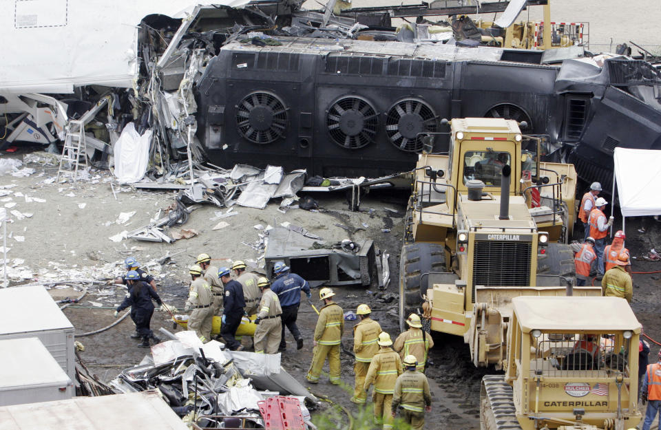 FILE - Emergency responders remove a body from the Metrolink commuter train that collided with a Union Pacific freight train the day before in Chatsworth, Calif., Sept. 13, 2008. Passenger railroads nationwide will now be required to install video recorders inside their locomotives, but the head of the National Transportation Safety Board said the new rule is flawed because it excludes freight trains like the one that derailed and caught fire in eastern Ohio, in February 2023. The NTSB made its recommendation to add cameras in locomotives in 2010 after it investigated the deadly 2008 collision between a Metrolink commuter train and a Union Pacific freight train. (AP Photo/ Rene Macura, File)