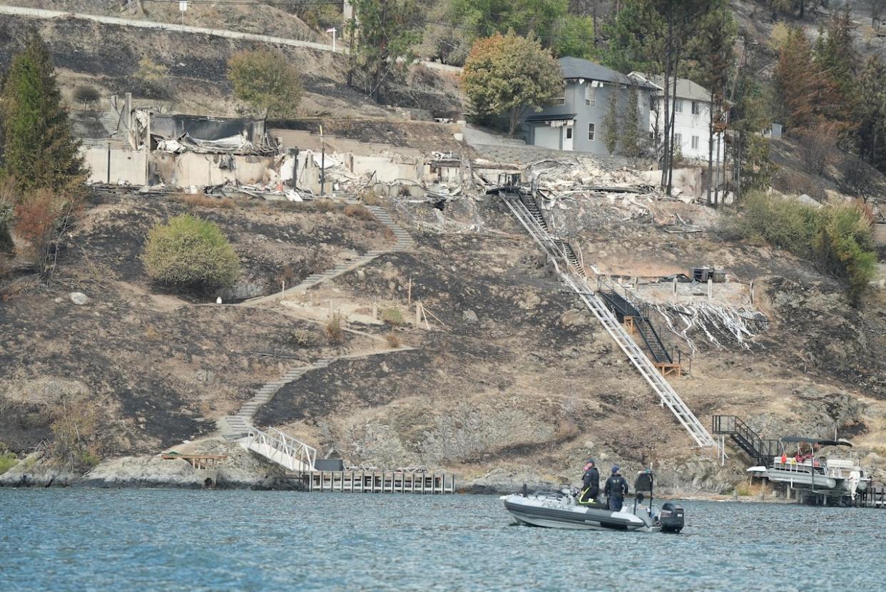 RCMP officers patrol Okanagan Lake near destroyed homes in West Kelowna on Aug. 23. (Chris Corday/CBC - image credit)