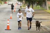Victor Castillo, right, runs with his grandson Julian Rubio, left, and their dog, Niko, during the second annual Lexi's Legacy Run, Saturday, Oct. 21, 2023, in Uvalde, Texas. (AP Photo/Darren Abate)