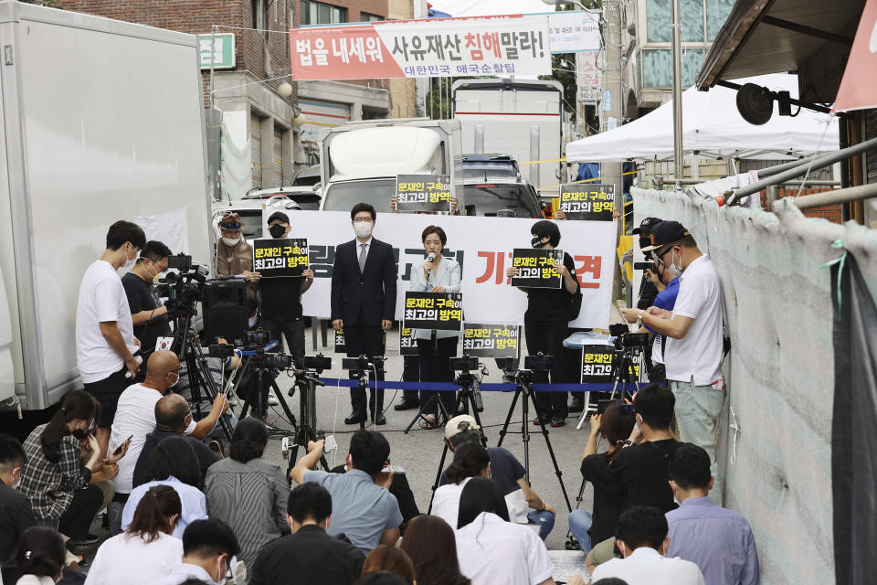 Sarang Jeil Church pastor Jun Kwang-hun's lawyer, Kang Yeon-jae, top center, speaks during a press conference near the church in Seoul, South Korea, Monday, Aug. 17, 2020. Jun who has been a bitter critic of the country's president has tested positive for the coronavirus health authorities said Monday, two days after he participated in an anti-government rally in Seoul that drew thousands. The signs read "Moon Jae-in's arrest is best quarantine."(Lim Hwa-young/Yonhap via AP)