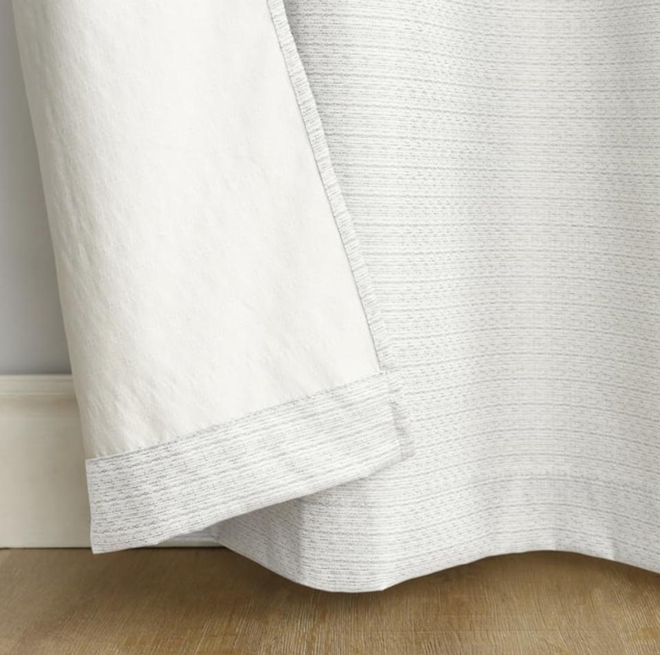 Close-up of a white textured bedspread with a detailed view of the fabric and hem.