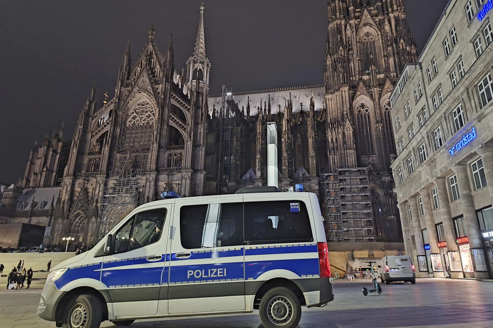 A police vehicle is parked in front of the cathedral in Cologne, Germany, Saturday, Dec. 23, 2023. Cologne police acting on indications of a possible attack searched Germany's landmark cathedral with sniffer dogs Saturday and said worshippers attending Christmas Eve Mass would undergo security screening before being allowed in. (Sascha Thelen/dpa via AP)