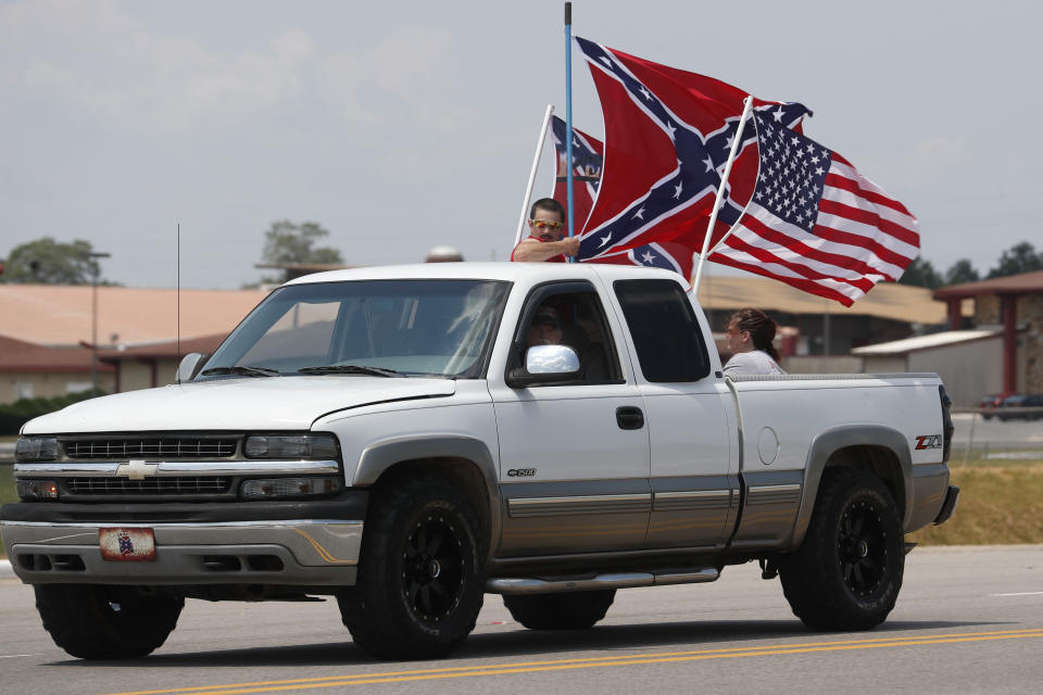 FILE - In this June 21, 2020, file photo, race fans fly Confederate battle flags and a United States flag as they drive by Talladega Superspeedway prior to a NASCAR Cup Series auto race in Talladega, Ala. The Confederate battle flag is losing its place of official prominence in the South 155 years after the end of the Civil War. NASCAR, has banned the rebel banner from its car races. (AP Photo/John Bazemore, File)