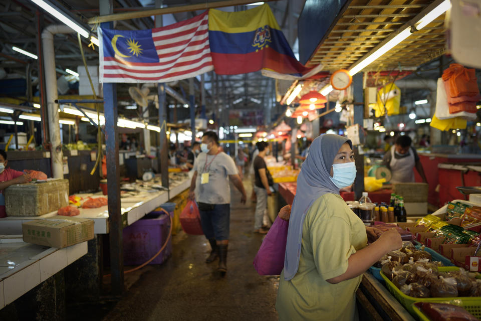 A woman wearing a face mask to help stop the spread of the coronavirus shops at a wet market in downtown Kuala Lumpur, Malaysia, Friday, April 24, 2020. Malaysia, along with neighboring Singapore and Brunei, has banned popular Ramadan bazaars where food, drinks and clothing are sold in congested open-air markets or road-side stalls. The bazaars are a source of key income for many small traders, some who have shifted their businesses online. (AP Photo/Vincent Thian)