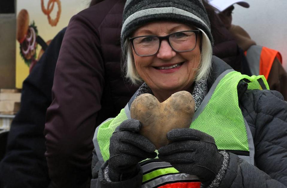 A volunteer holds up a heart shaped potato she discovered while bagging and sorting produce Friday morning for the 2nd Harvest Mobile Market event held in the parking lot of the LifeChurch7 in Richland. About 50 volunteers from the church and Energy Northwest were on hand to help give out free food for about 250 Mid-Columbia families.