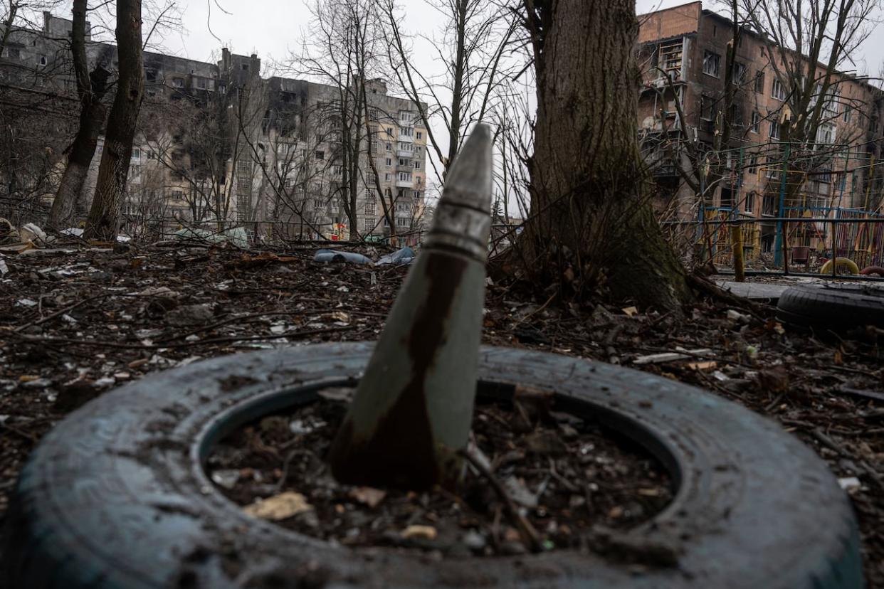 A part of a rocket sticks up from the ground in front of a residential building bombed by Russian forces in the frontline city of Vuhledar, Ukraine on Feb. 25, 2023. Russia is investing heavily in infrastructure in occupied Ukraine, and Ukraine is asking allies for aid and investment to repair its shattered infrastructure. (Evgeniy Maloletka/Associated Press - image credit)