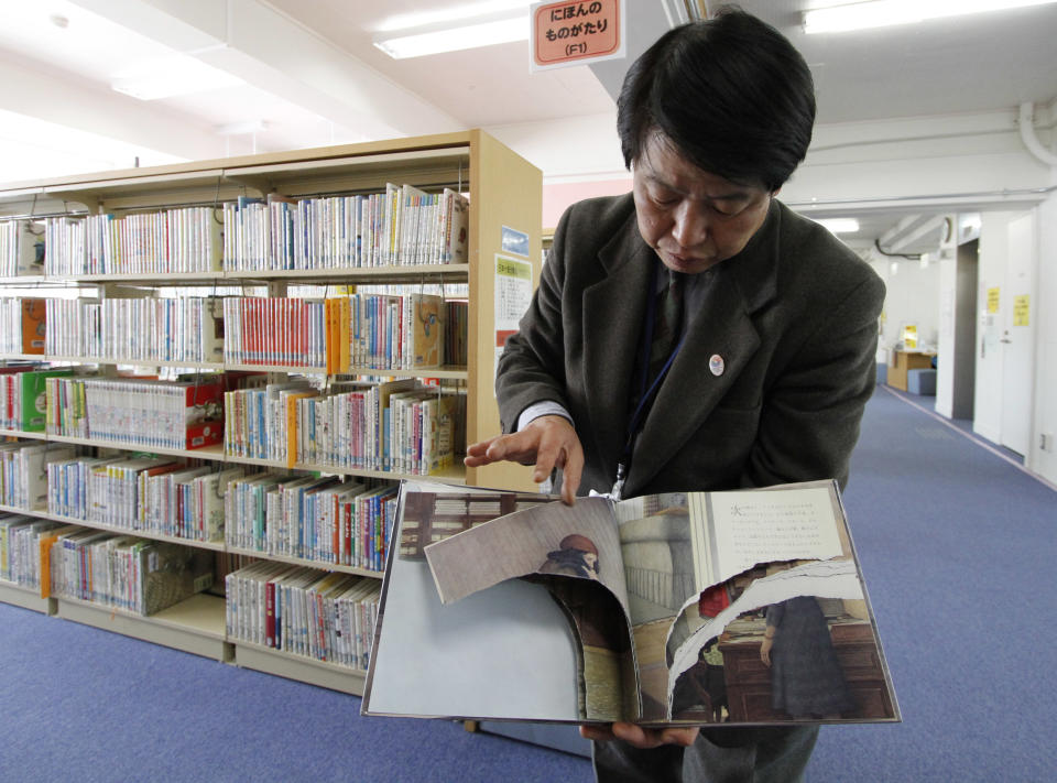 A ripped copy of Anne Frank's "Diary of a Young Girl" picture book is shown by Shinjuku City Library Director Kotaro Fujimaki at the library in Tokyo Friday, Feb. 21, 2014. Tokyo Libraries said on Friday that hundreds of copies of Anne Frank's diary and related books have been found vandalised across the city's libraries in the last month, sparking fears of an anti-Semitic motive. A total of 265 books in 31 libraries had been found damaged after the first damaged book was found in January, prompting a wider search. (AP Photo/Koji Ueda)
