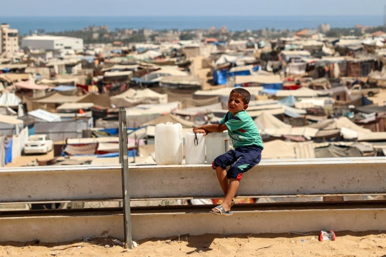 Un niño permanece sentado junto a unas garrafas de agua en una valla de un campo de desplazados en Rafah, el 25 de junio de 2024 en esa ciudad al sur de la Franja de Gaza (Eyad Baba)