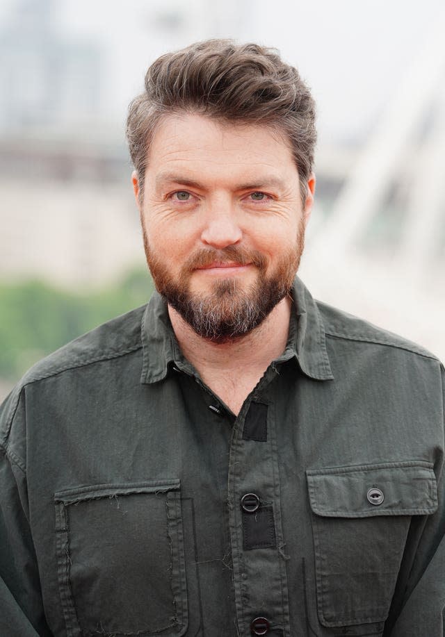 Tom Burke smiling while wearing black shirt