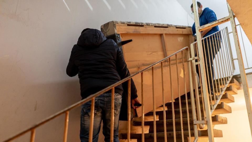 Two people moving a sofa up a flight of stairs