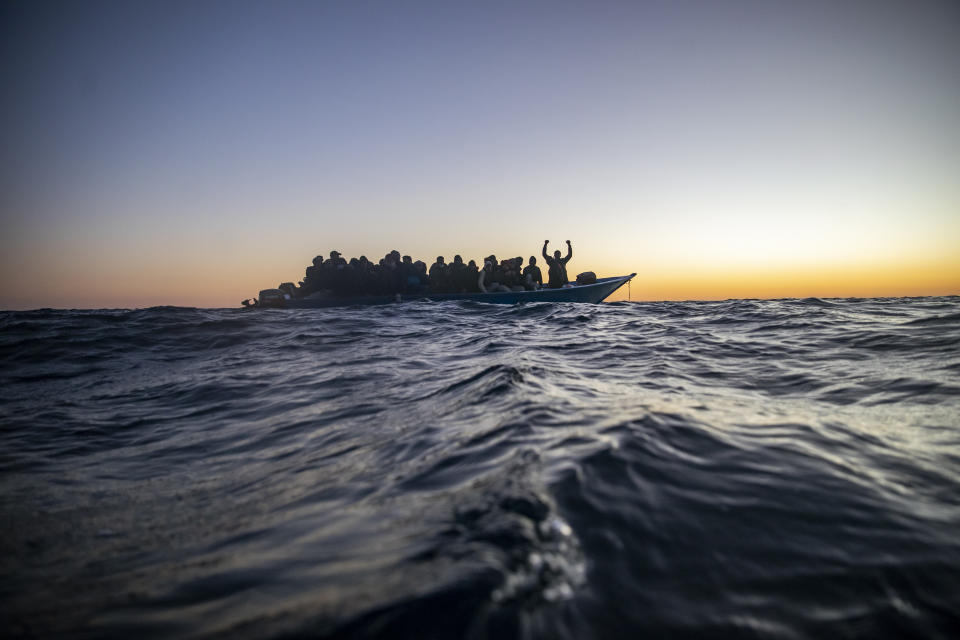 Migrantes y refugiados de distintos países de África viajan a bordo de una atestada embarcación de madera mientras rescatistas de la ONG española Open Arms se acercan a ellos en aguas internacionales del Mar Mediterráneo, a 122 millas de la costa de Libia, el 12 de febrero de 2021. En los últimos días, las autoridades libias han impedido ocho intentos de rescate por parte del Open Arms, el barco de la ONG española del mismo nombre, acosando y amenazando a su tripulación. (AP Foto/Bruno Thevenin)