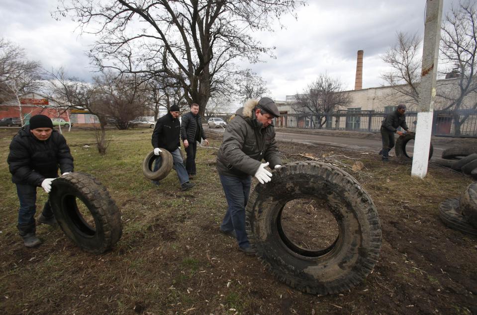 Pro Russian activists block a road with car tires near the armory Ukrainian army to prevent the export of arms and ammunition in the village of Poraskoveyevka, eastern Ukraine, Thursday, March 20, 2014. The disheveled men barricading the muddy lane leading into a military base in this eastern Ukraine village say they're taking a stand to defend Russian-speakers. (AP Photo/Sergei Grits)