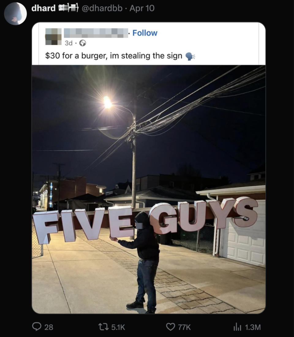 Person holding a large "FIVE GUYS" sign at night on a street
