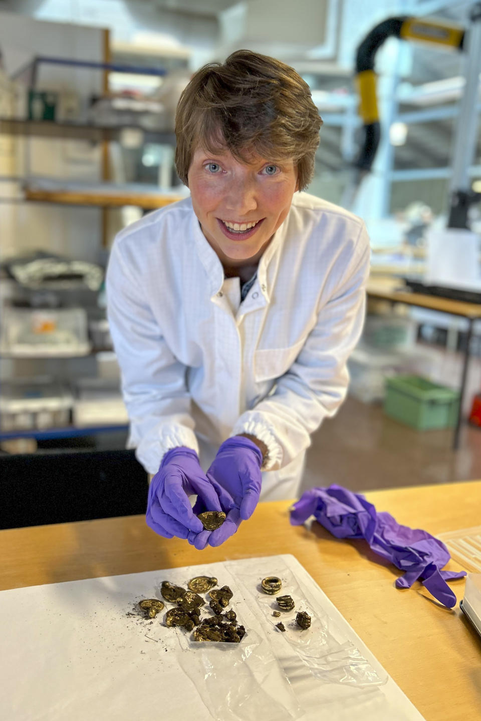 Conservator Hege Hollund at the Archaeological Museum, University of Stavanger looks at the gold found by Erlend Bore with a metal detector on the island of Rennesoey in Stavanger, Norway, Thursday Sept. 7, 2023. Bore found nine pendants, three rings and 10 gold pearls on a southern island in what was described as the gold find of the century in Norway. (Anniken Celine Berger/Archaeological Museum, UiS via NTB via AP)