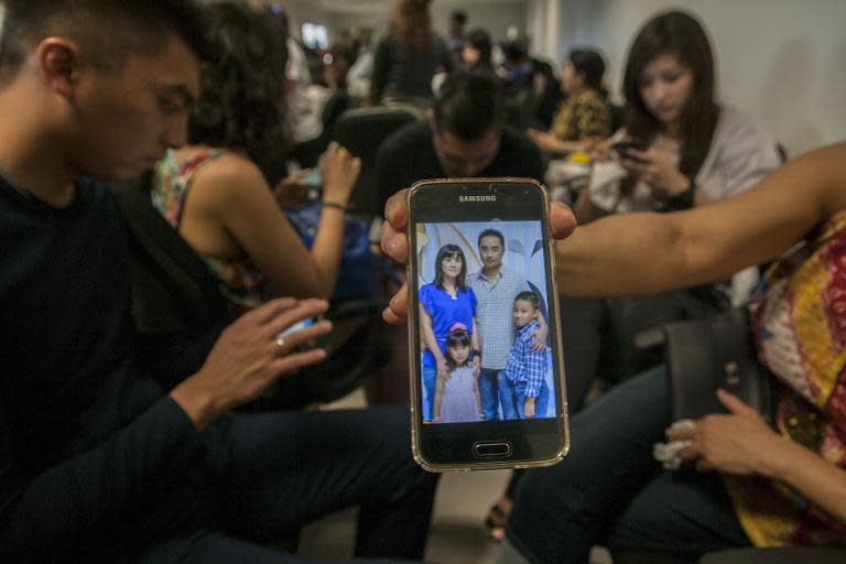 A relative shows a picture of passengers who are travelling on the missing AirAsia plane on her mobile phone screen at the airport in Surabaya, East Java