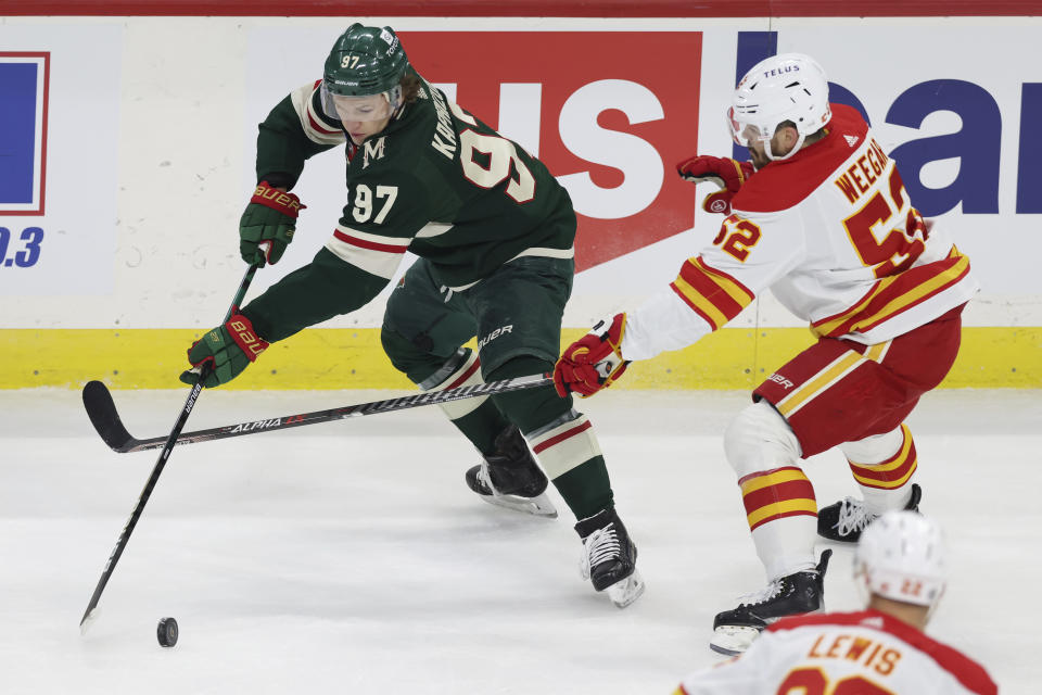 Minnesota Wild left wing Kirill Kaprizov (97) handles the puck against Calgary Flames defenseman MacKenzie Weegar (52) during the first period of an NHL hockey game Tuesday, March 7, 2023, in St. Paul, Minn. (AP Photo/Stacy Bengs)