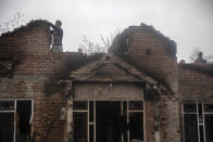 Kashmiri villagers inspect a house that was damaged during a gun battle between government forces and suspected rebels in Bijbehara, some 28 miles (45 kilometers) south of Srinagar, Indian controlled Kashmir, Sunday, April 11, 2021. (AP Photo/Mukhtar Khan)