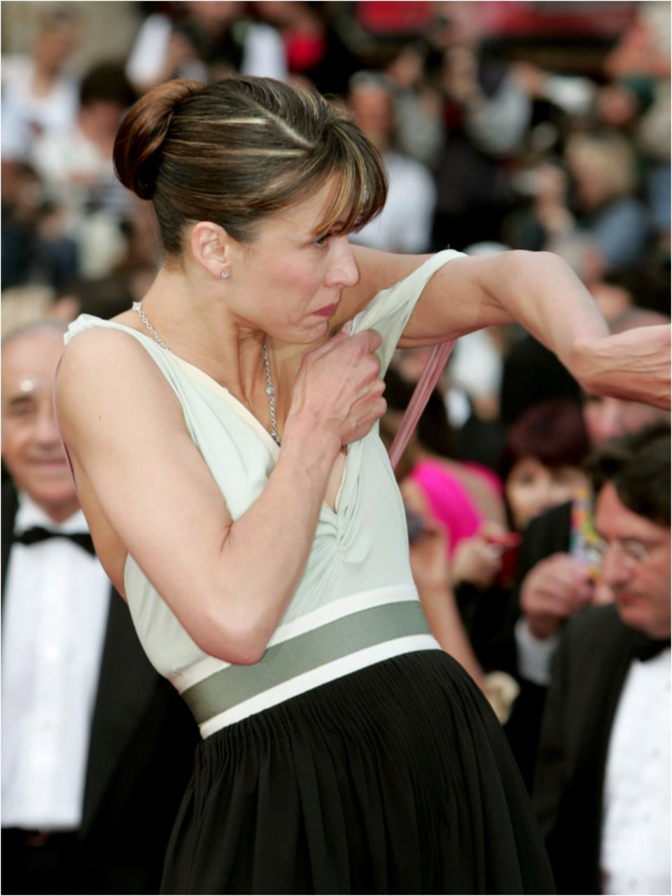 Sophie lifting up left side of her ceam bodice and strap back over her shoulder.