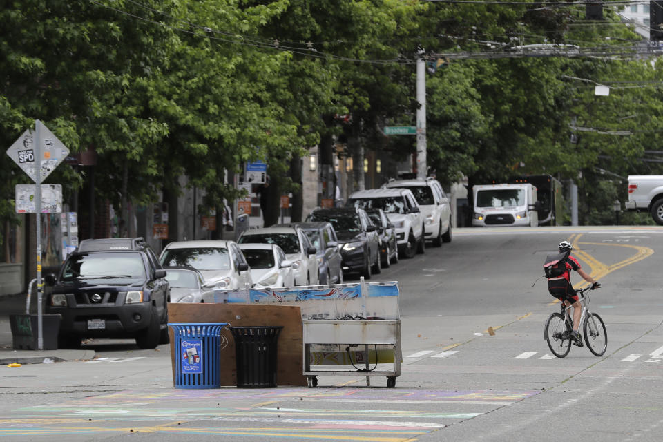 A cyclist rides past what remains of makeshift barricades that were put in place by protesters at the intersection of 10th Ave. and Pine St., Tuesday, June 30, 2020 after Seattle Department of Transportation workers removed concrete barricades from the intersection at the CHOP (Capitol Hill Occupied Protest) zone in Seattle. The area has been occupied by protesters since Seattle Police pulled back from their East Precinct building following violent clashes with demonstrators earlier in the month. (AP Photo/Ted S. Warren)