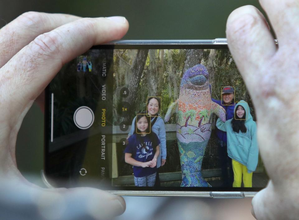 A family takes a snapshot while checking out the manatees packed into the spring run Thursday at Blue Spring State Park.