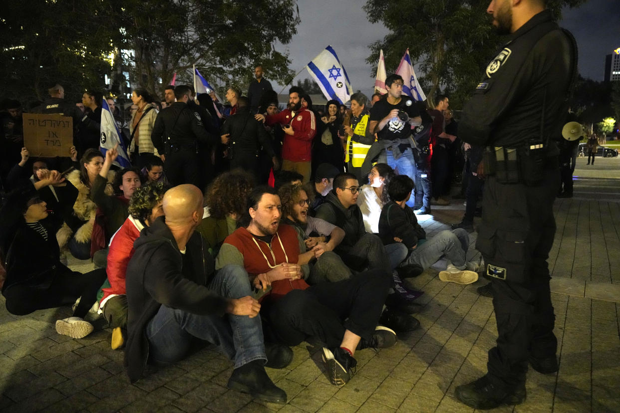 Activists lock arms in Tel Aviv, Israel, to protest against Prime Minister Benjamin Netanyahu's far-right government, Saturday, Jan. 7, 2023. Thousands of Israelis protested plans by Netanyahu's government that opponents say threaten democracy and freedoms. (AP Photo/ Tsafrir Abayov)