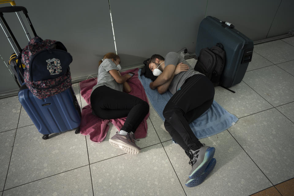 Una pareja argentina descansa mientras espera a que autoridades organicen transporte para llevarlos a la provincia de Mendoza después de haber llegado desde Colombia al aeropuerto internacional de Ezeiza en Buenos Aires, Argentina, el lunes 23 de marzo de 2020. (AP Foto/Victor R. Caivano)