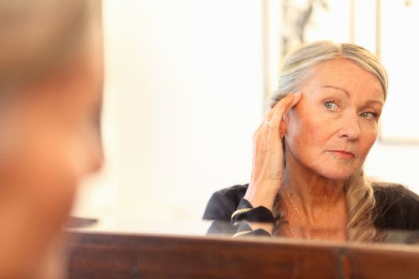 Older woman applying makeup in mirror