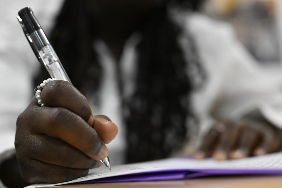 A girl holding a pen takes notes during class.