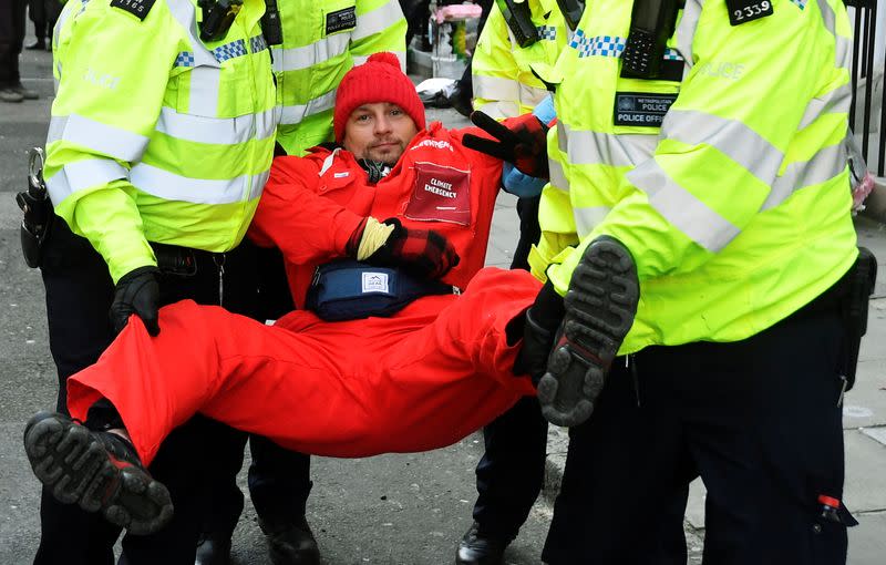 Greenpeace climate activist looks on as he is being removed by police officers near the entrance to BP's head office in London