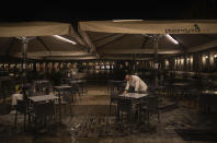 A waiter closes the terrace of a bar on the Mayor square in downtown Madrid, Spain, Friday, Oct. 23, 2020. (AP Photo/Manu Fernandez)