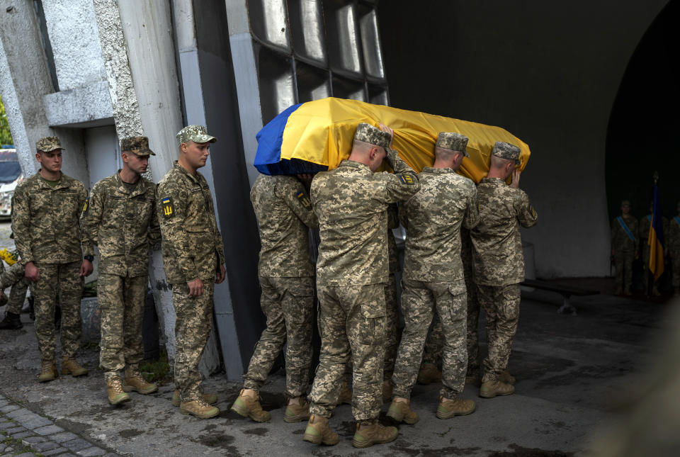 Servicemen carry the coffin of Olga Simonova, 34, a Russian woman who was killed in the Donetsk region while fighting on Ukraine's side in the war with her native country, in a crematorium in Kyiv, Ukraine, Friday, Sept. 16, 2022. 2022. (AP Photo/Roman Hrytsyna)