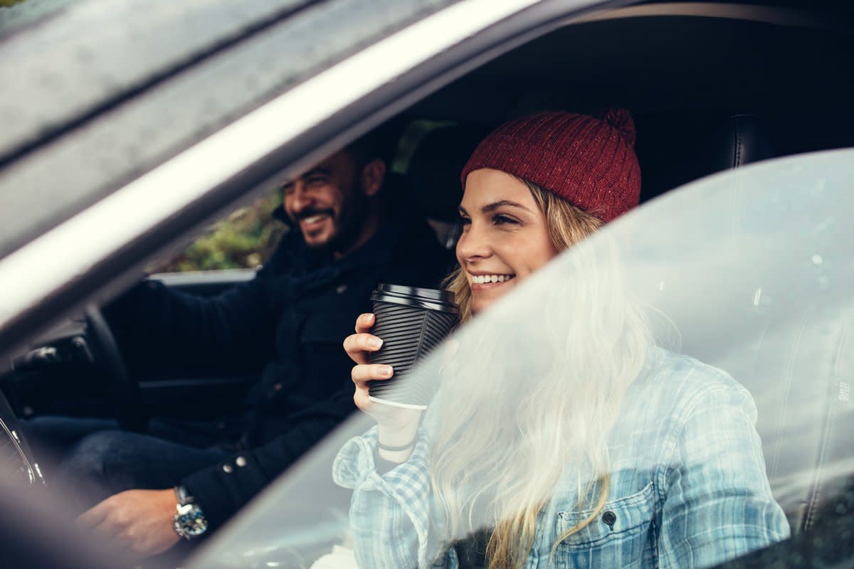 A young woman sips on coffee as she is about to leave on a road trip. 