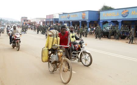 Civilians travel past Congolese soldiers gathering after patrolling to prevent protests against the government's failure to stop the killings and inter-ethnic tensions in the town of Butembo, North Kivu province in the Democratic Republic of Congo, August 25, 2016. REUTERS/Kenny Katombe