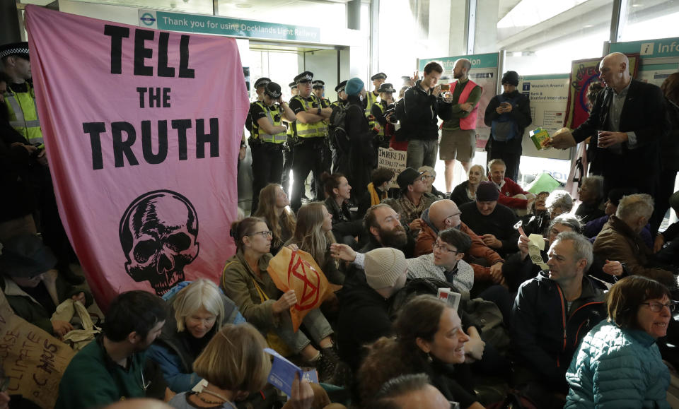 Police Officers stand guard as Extinction Rebellion demonstrators peacefully block an entrance at City Airport in London, Thursday, Oct. 10, 2019. Some hundreds of climate change activists are in London during a fourth day of world protests by the Extinction Rebellion movement to demand more urgent actions to counter global warming. (AP Photo/Matt Dunham)